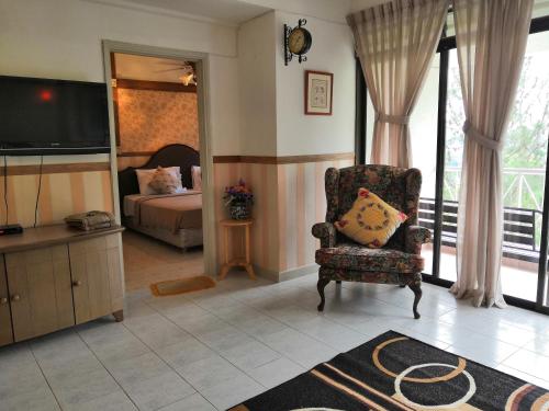 ein Schlafzimmer mit einem Bett und einem Stuhl und einem Fernseher in der Unterkunft Genting Sempah Berjaya Hill Cottage in Bukittinggi