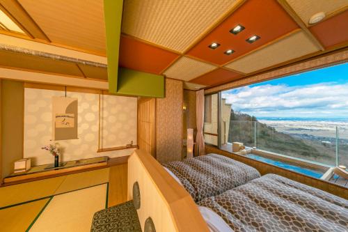 Cette chambre comprend deux lits et une grande fenêtre. dans l'établissement Takimotokan Yuki No Sato, à Yoro