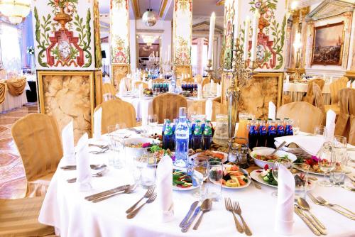 una sala da pranzo con tavoli bianchi con piatti di cibo di Hotel Książę Poniatowski a Lesznowola