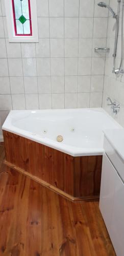 a bath tub in a bathroom with a wooden floor at Astley Cottage in Daylesford