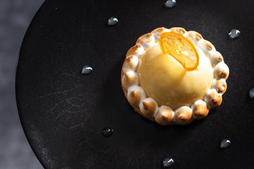 a dessert with an orange on top of a black plate at Hotel Les Arolles in Méribel