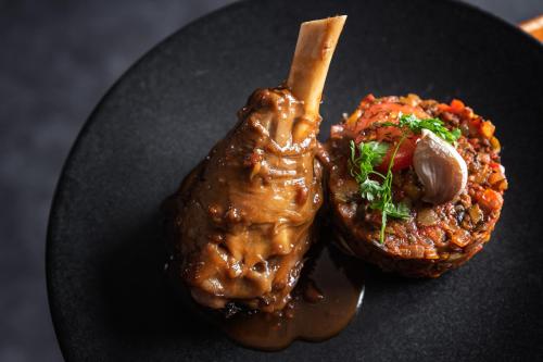 a black plate with a piece of meat and food on it at Hotel Les Arolles in Méribel
