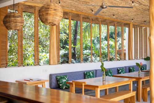 a restaurant with wooden tables and chairs and windows at The Nomadic Hotel in Nosara