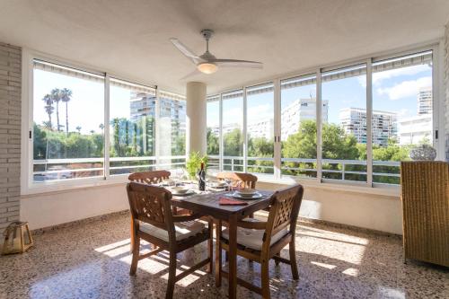 a dining room with a table and chairs and large windows at Villamar - Relax, Sol y Playa in Alicante
