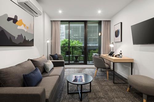 a living room with a couch and a desk at Quest NewQuay in Melbourne