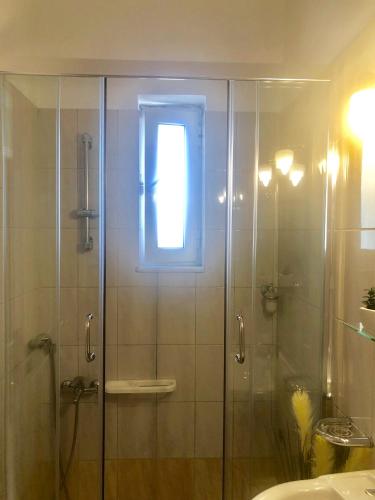 a glass shower with a window in a bathroom at Lovely Apartments D in Patra