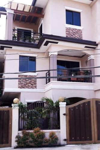 a white house with a gate and a fence at Elaine's Homestay in Dumaguete
