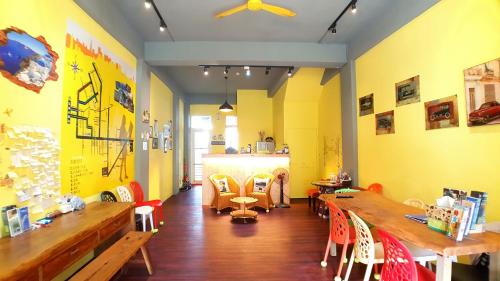un restaurante con mesas y sillas de madera y paredes amarillas en 站前海民宿 en Hualien