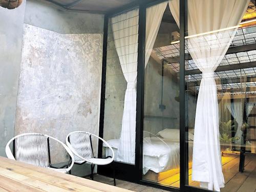 une pièce avec deux chaises et une fenêtre avec un lit dans l'établissement Rimba Jonker, Melaka Heritage Residance, à Malacca