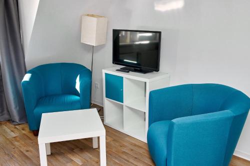 a living room with two blue chairs and a tv at Townhouse Duderstadt in Duderstadt