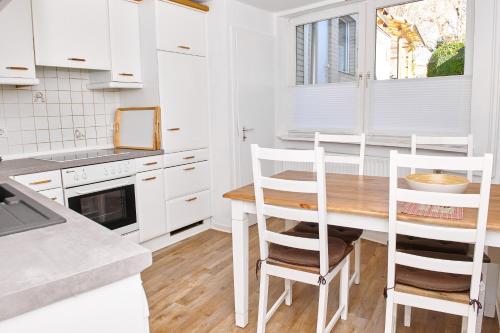 a kitchen with white cabinets and a wooden table and chairs at Townhouse Duderstadt in Duderstadt