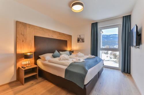 a bedroom with a large bed with a large window at Lake Resort Pressegger See in Hermagor