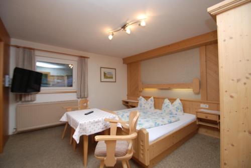 a bedroom with a bed and a table and a television at Ferienwohnung Pension Tirol in Bichlbach