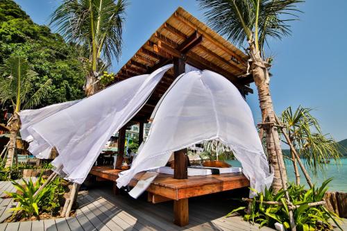 two white umbrellas on a beach with the ocean at Phi Phi CoCo Beach Resort in Phi Phi Don