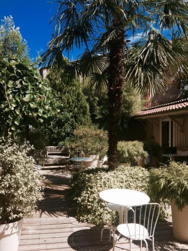 a patio with a table and chairs and a palm tree at Maison du Lierre Bordeaux Centre ville in Bordeaux