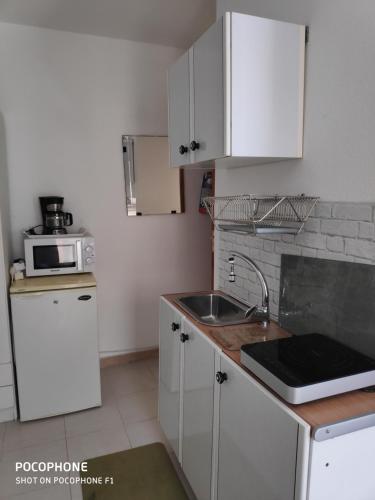 a kitchen with white cabinets and a sink and a microwave at Eco in Caleta De Fuste