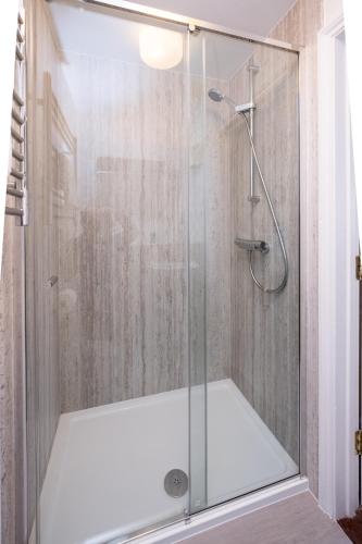 a shower with a glass door in a bathroom at Ogilvie Lodge Apartment in Thorpeness