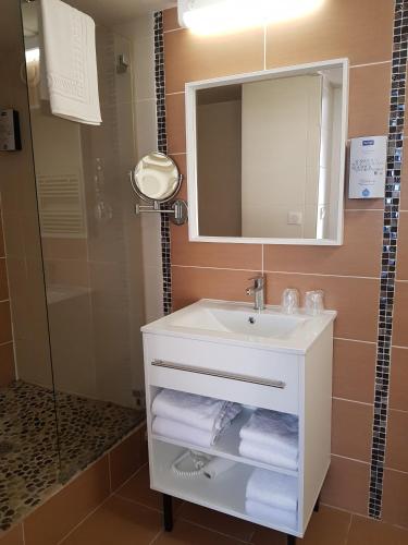 a bathroom with a sink and a mirror and towels at KYRIAD LYON EST – Saint Quentin Fallavier in Saint-Quentin-Fallavier