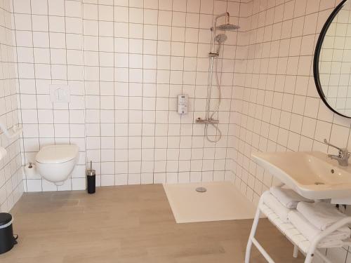 a white tiled bathroom with a toilet and a sink at KYRIAD LYON EST – Saint Quentin Fallavier in Saint-Quentin-Fallavier