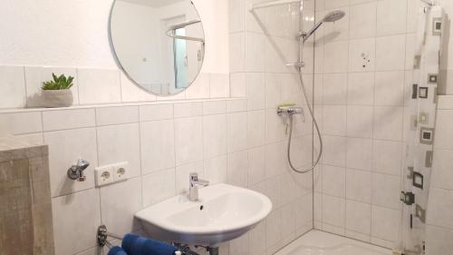 a white bathroom with a sink and a shower at Ferienwohnung am Waldrand in Herdwangen-Schönach