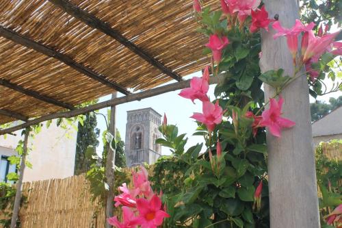 a pergola with pink flowers in front of a building at Gelsomino Rooms Ravello in Ravello