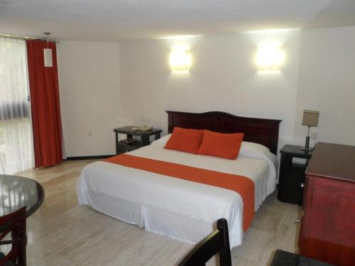 a bedroom with a bed with two orange pillows on it at Hotel Poza Rica Inn in Poza Rica de Hidalgo