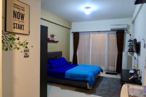 a bedroom with a blue bed and a window at Bacup Studio Apartment @Galeri Ciumbuleuit in Bandung