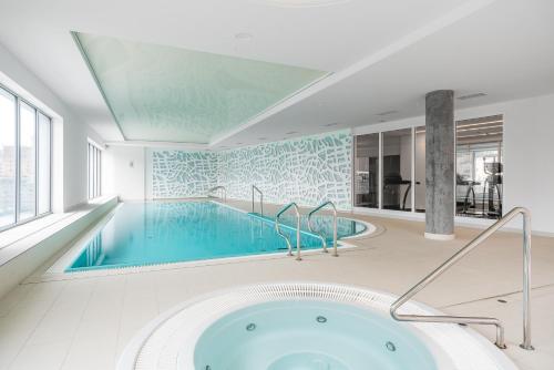 a large swimming pool with a tub in a room at Marinus Apartments SPA - with pool and sauna in Gdańsk