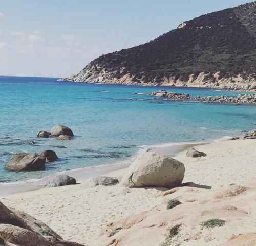 a beach with rocks and water and a mountain at Villa Sardinia Seaview&SPApool in Villasimius