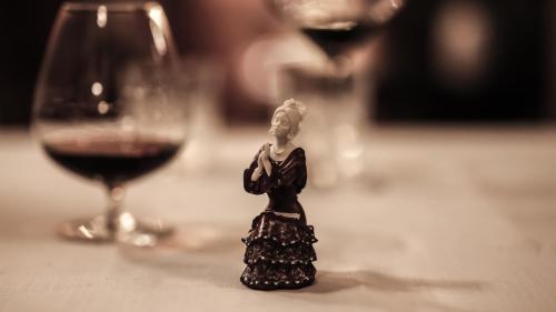 a figurine of a woman next to a glass of wine at Hotel Casa Palacio María Luisa in Jerez de la Frontera