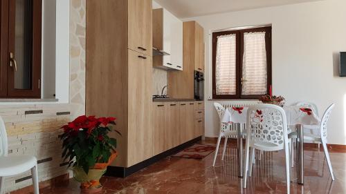 a kitchen with white chairs and a table and a window at Da Pietro in Pietra in La Martella