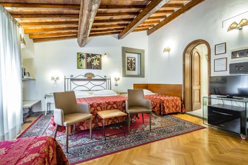 a bedroom with a bed and two chairs and a television at Hotel Collodi Firenze in Florence