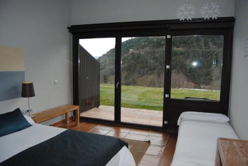 a bedroom with two beds and a large glass window at Hotel Rural-Spa Resguard Dels Vents in Ribes de Freser