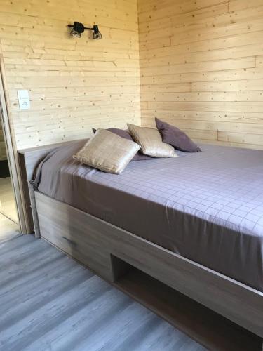 Cama en habitación de madera con 2 almohadas en Gîte pour 4 personnes, en Saint-Martin-du-Fouilloux