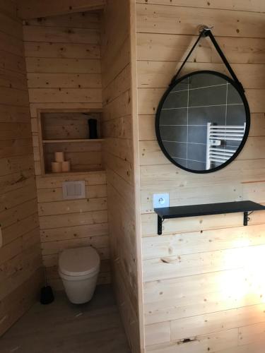 uma casa de banho com um WC e um espelho redondo em Gîte pour 4 personnes em Saint-Martin-du-Fouilloux