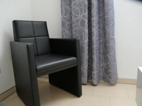 a black chair sitting in front of a curtain at Apartment FALVIG inkl. Küche in Bad Schonborn