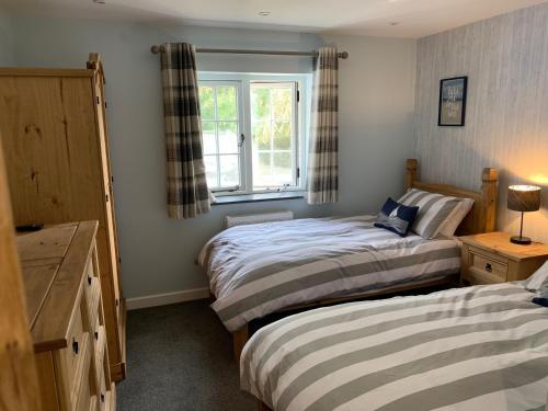 a bedroom with two beds and a window at Bossiney Cove Cottage in Tintagel