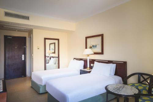 a hotel room with two beds and a table at Swiss Inn Resort Hurghada in Hurghada