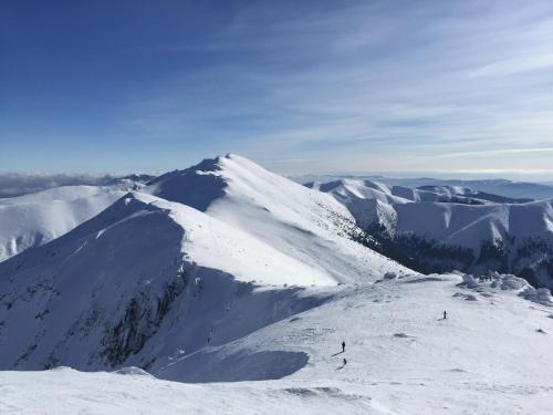 a snow covered mountain with people skiing on it at Apartmán Ježko in Tale
