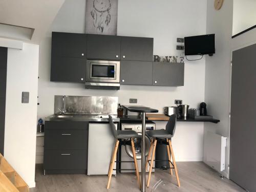 クレルモン・フェランにある2 Lofts Cosy de cachet idéalement situés au Centre Ville de Clermont-Ferrandのキッチン(黒いキャビネット、テーブル、椅子付)