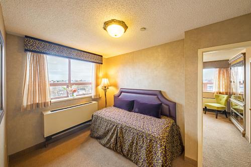 a bedroom with a bed with purple pillows and a window at The Avenue Plaza in Brooklyn