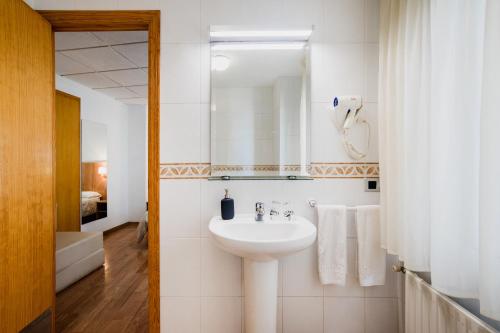 a white bathroom with a sink and a mirror at Hotel El Cid in Morella