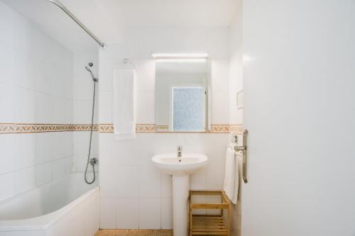 a white bathroom with a sink and a bath tub at Hotel El Cid in Morella