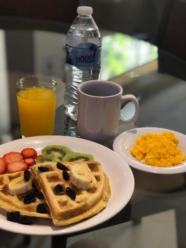 a plate of breakfast food with waffles and a cup of orange juice at Summer House Inn San Andres in San Andrés