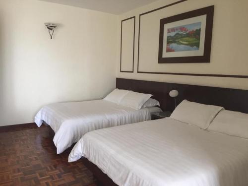 two beds in a hotel room with white sheets at D savoy @ Famosa by MR in Melaka