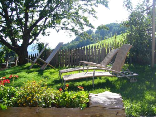 two chairs in a yard with flowers and a fence at Appartements Kerschbaumer in Feldthurns