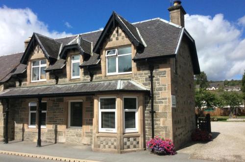 une maison en briques avec un toit noir dans l'établissement Clune House B&B, à Newtonmore