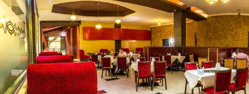 a dining room with red chairs and tables in a restaurant at Freedom City Hotel Najjanankumbi Kamapala in Kampala