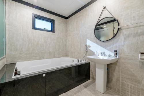 a bathroom with a tub and a sink and a mirror at Air Sky Hotel in Busan