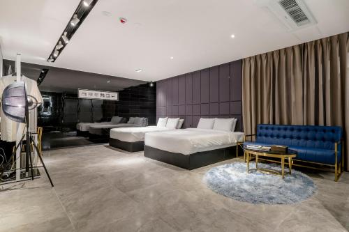a hotel room with two beds and a blue couch at Air Sky Hotel in Busan